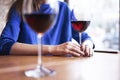 Woman is drinking red wine and having rest in cafe near window, close-up of womanÃ¢â¬â¢s hands holding glass on table Royalty Free Stock Photo